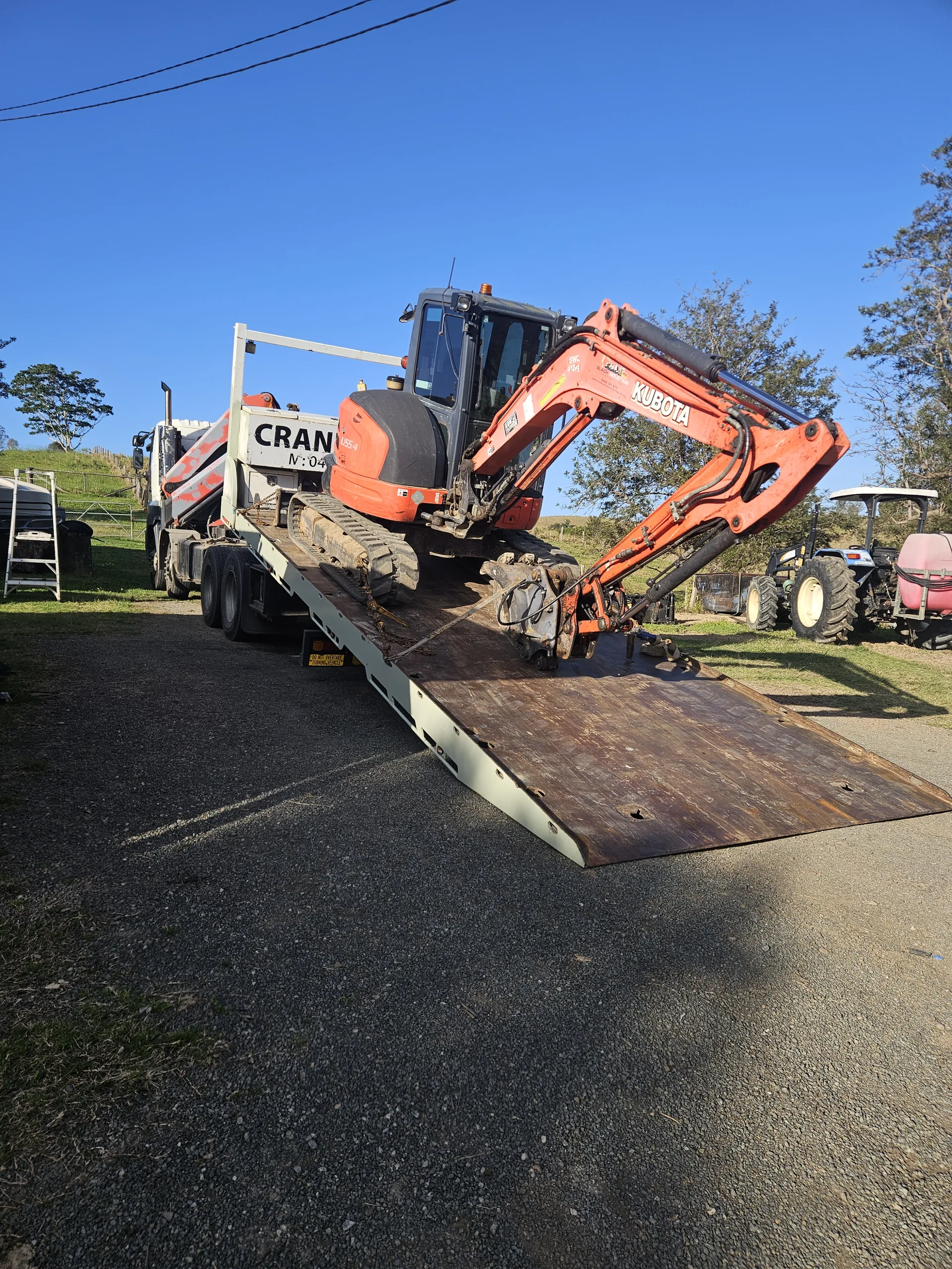 Excavator positioned on the lowered tilt tray for machinery transport
