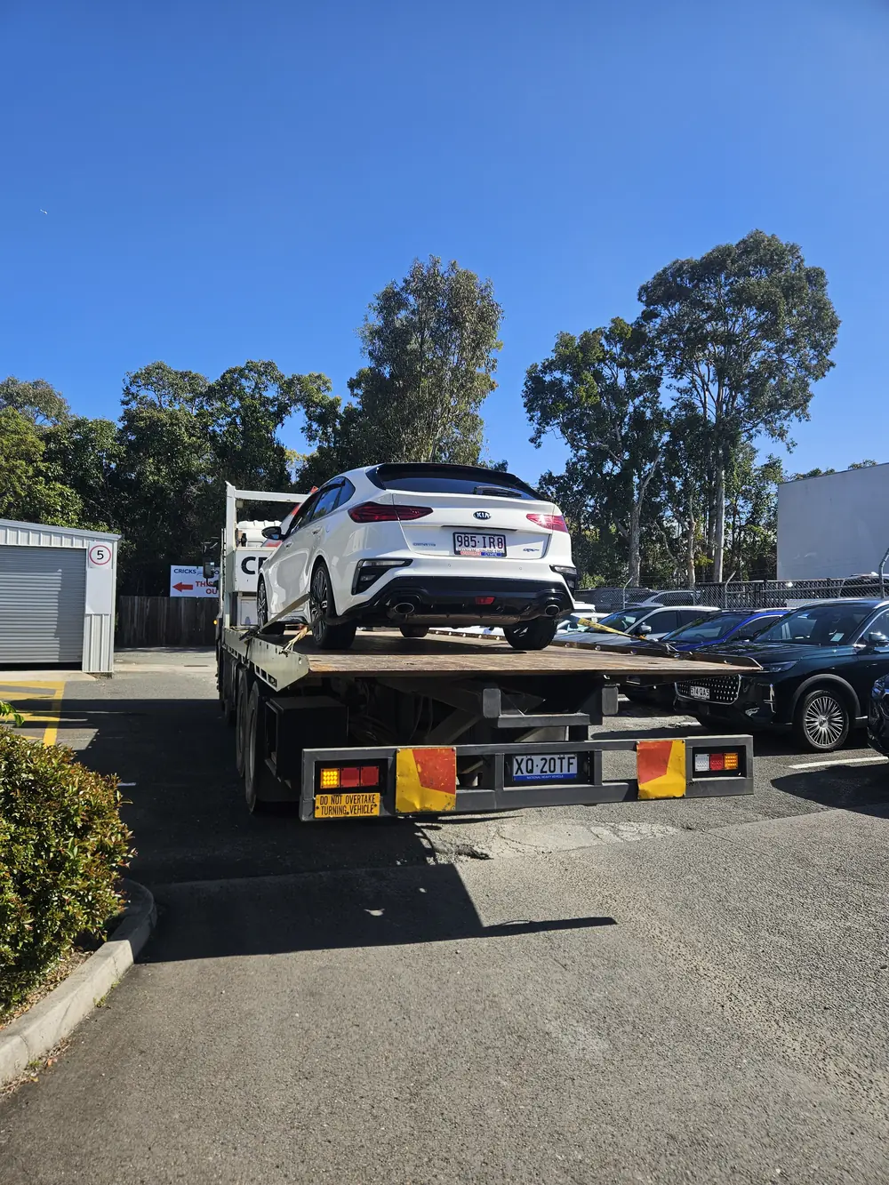 White vehicle secured on the tilt tray for transport
